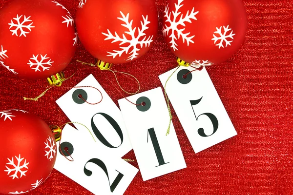 New year 2015 on tags and Christmas balls on red background — Stock Photo, Image