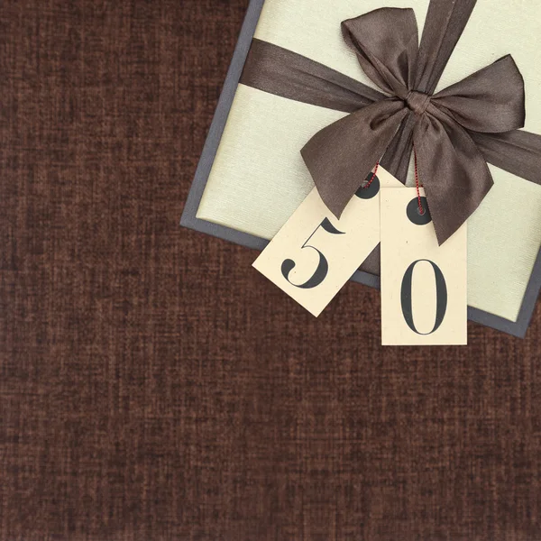 Подарункова коробка зі стрічкою та номером 50 на коричневому фоні — стокове фото