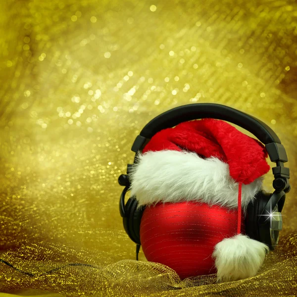 Christmas ball with headphones in glittering background — Stock Photo, Image