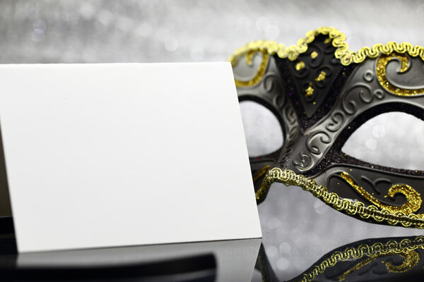 Винтажная карнавальная маска и белая пустая карточка перед блестящим фоном
