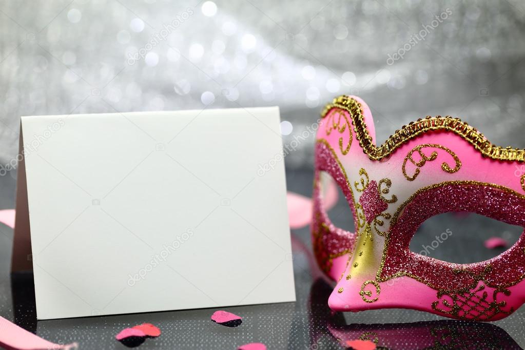 Vintage carnival mask and white blank card in front of glittering background