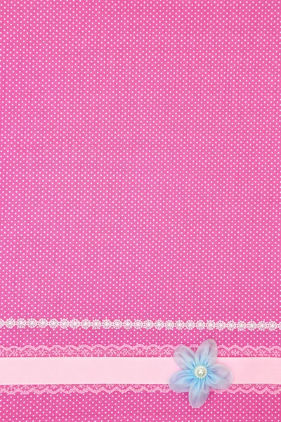 Розовый горошек текстильный фон с лентой и цветком — стоковое фото