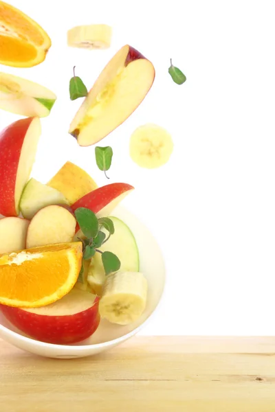 Salade de fruits frais avec morceaux sortis d'un bol isolé — Photo