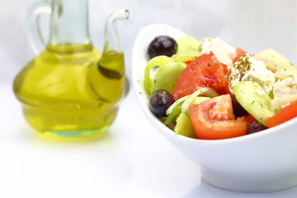 Miska ze świeżymi sałatkami i oliwy z oliwek na stole — Zdjęcie stockowe