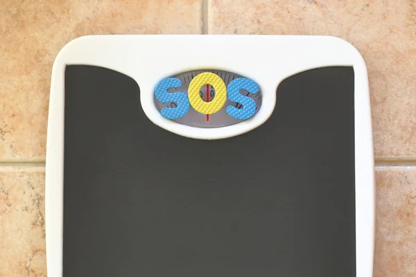 Bilancia da bagno con testo SOS. Concetto di dieta — Foto Stock