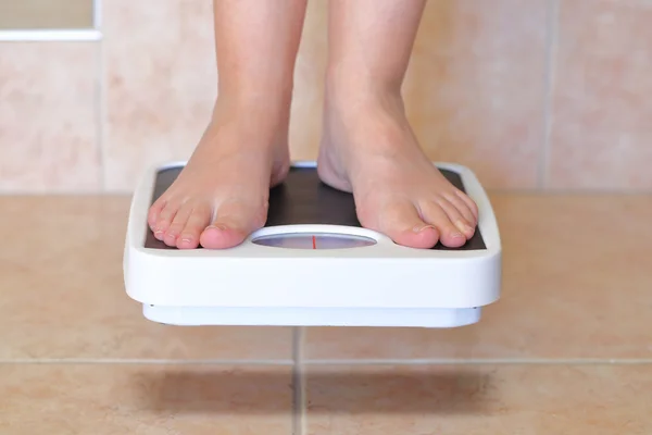 Woman's feet and bathroom scale hovers above the floor — Stock Photo, Image