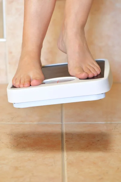 Женские ступни и весы в ванной висят над полом — стоковое фото