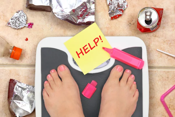 Pies en la escala del baño con la palabra Ayuda y basura comida chatarra — Foto de Stock