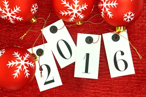 New year 2016 on tags and Christmas balls on red background — Stock Photo, Image