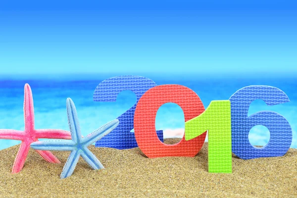 New year number 2016 and starfishes on the beach — Stock Photo, Image