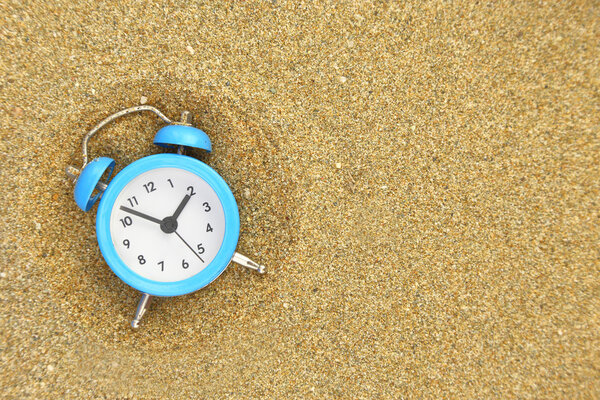 Vacation time. Alarm clock on the sand