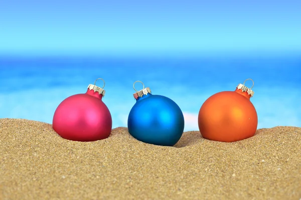 Christmas balls on sandy beach — Stock Photo, Image