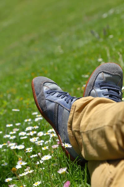 Feet in shoes on green field with flowers — Stock Photo, Image