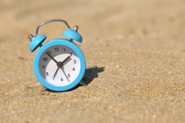 Vacation time. Alarm clock on the sand