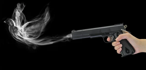 Hand holding a smoking gun isolated on black — Stock Photo, Image
