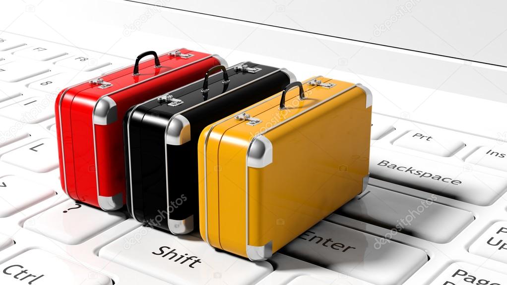 Colorful suitcases on white laptop keyboard