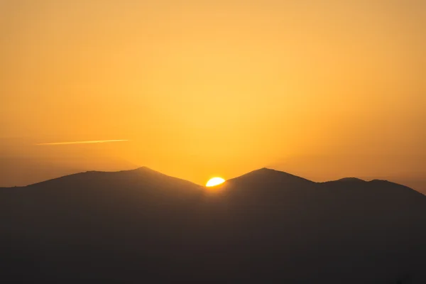 Vista panorâmica de um belo pôr-do-sol laranja sobre as silhuetas negras das montanhas — Fotografia de Stock