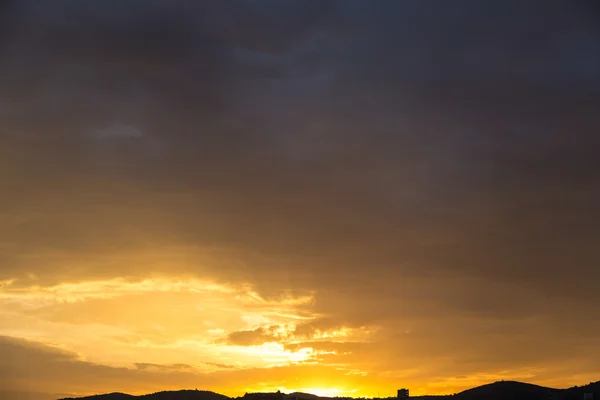 Γραφική θέα του ένα όμορφο πλούσιο πορτοκαλί ηλιοβασίλεμα πάνω από τις μαύρες σιλουέτες των βουνών — Φωτογραφία Αρχείου