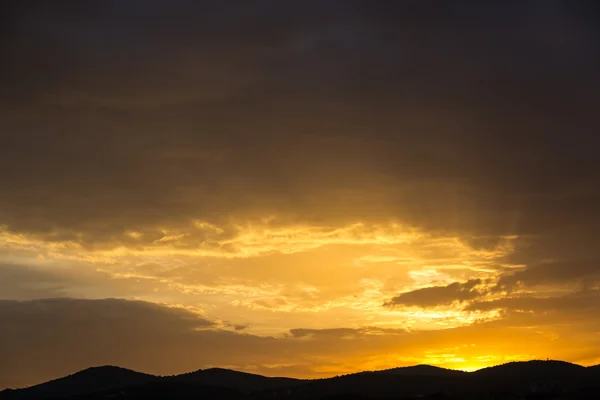 Vista panoramica di un bellissimo tramonto arancione sulle sagome nere delle montagne — Foto Stock