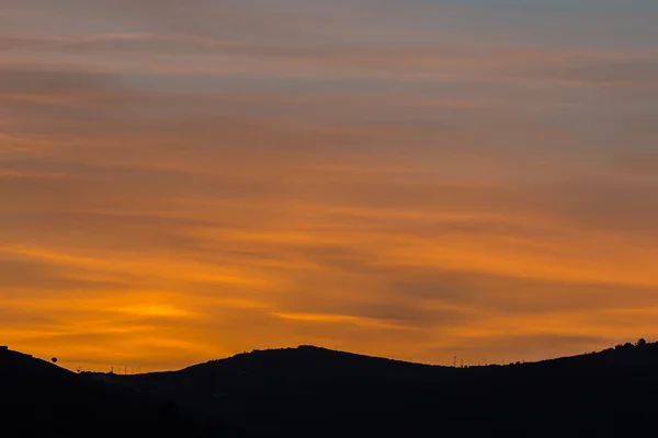Vista panoramica di un bellissimo tramonto arancione sulle sagome nere delle montagne — Foto Stock