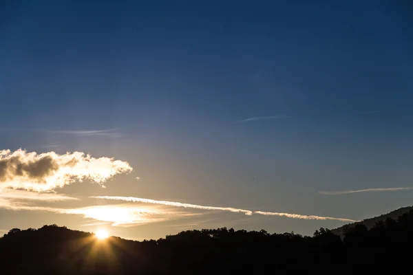 Vista panorámica de la puesta de sol sobre las siluetas negras de las montañas —  Fotos de Stock