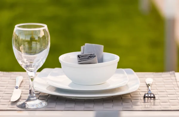 Elegante ciotola di stoviglie bianche, piatti e bicchieri di vino impostati sulla tavola — Foto Stock