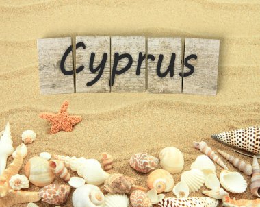 Cyprus on wooden board pieces with sea shells and sand