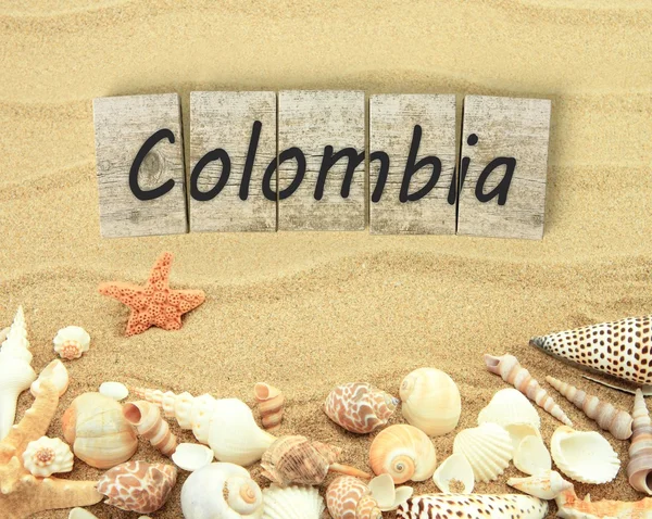 Colombia on wooden board pieces with sea shells and sand — Stock Photo, Image