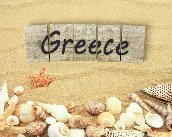 Greece on wooden board pieces with sea shells and sand — Stock Fotó