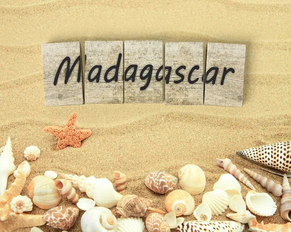 Madagascar on wooden board pieces with sea shells and sand — Stock Photo, Image