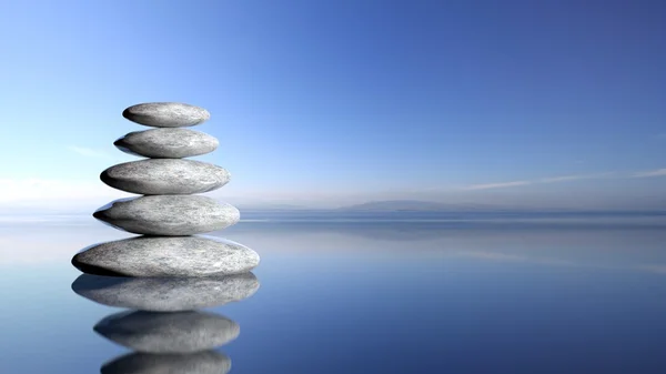 Zen stenen stapelen van grote naar kleine in water met een blauwe hemel en vreedzame landschap achtergrond. — Stockfoto