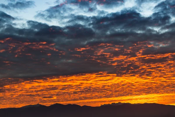 Vista panoramica di un bellissimo tramonto con cielo scuro e nuvole colorate sulle montagne — Foto Stock