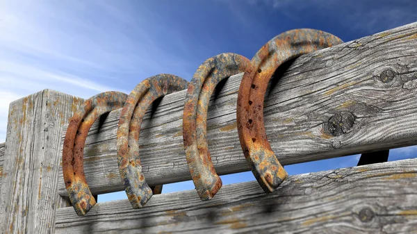 Old rusty horseshoes, set on wooden fence — Stock Photo, Image