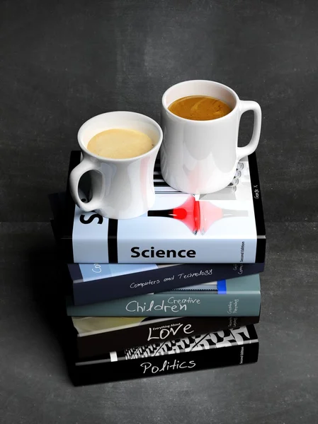 Stapel boeken met verschillende onderwerpen en twee kopjes koffie, met schoolbord achtergrond. — Stockfoto