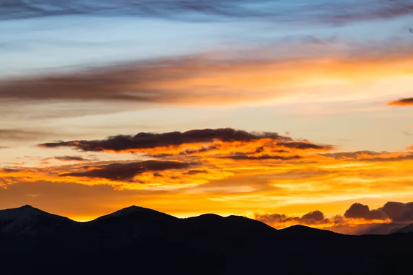 Majestic vivid sunset/sunrise with clouds over dark mountains silhouettes — Stock Photo, Image