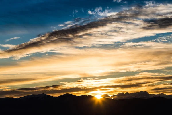 Maestoso tramonto vivido / alba con nuvole sulle sagome delle montagne scure — Foto Stock