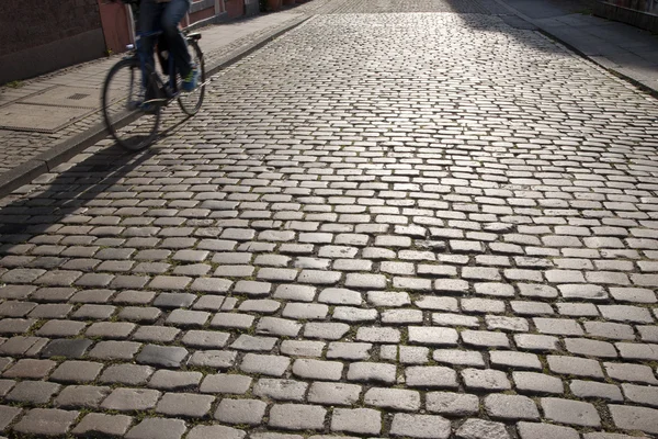 Cycliste et ombre sur pierres pavées — Photo