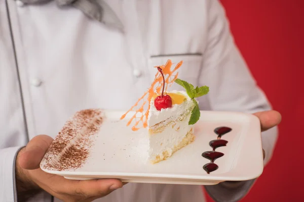 Homem de uniforme chef com bolo saboroso — Fotografia de Stock