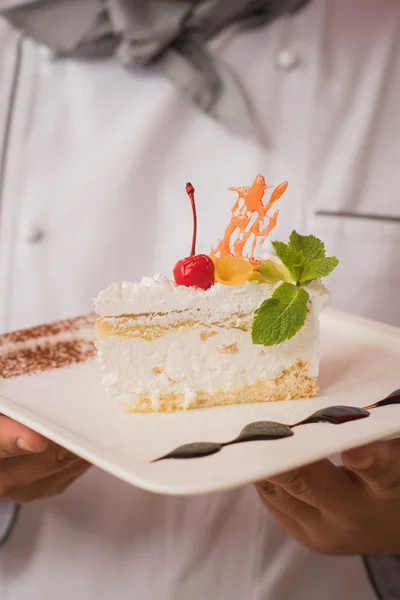 Homem de uniforme chef com bolo saboroso — Fotografia de Stock