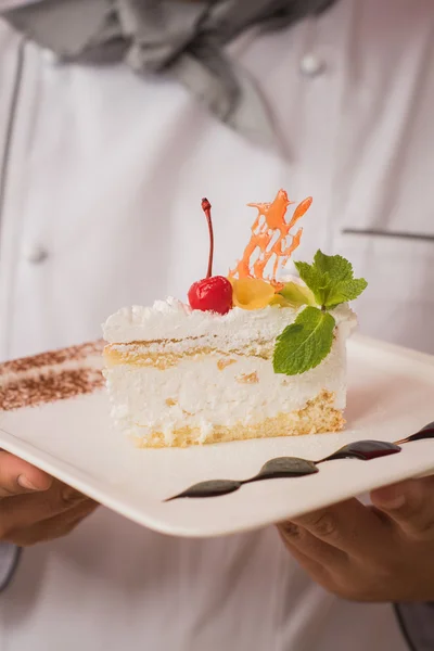 Uomo in uniforme da chef con gustosa torta — Foto Stock