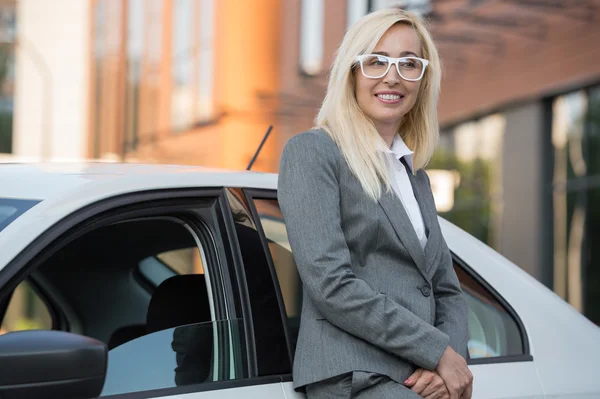 Businesswoman leaning on car — Stock Photo, Image