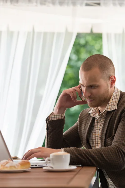 Uomo d'affari con cellulare che lavora su laptop — Foto Stock