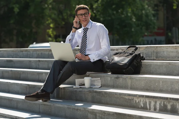 Man with laptop calling by phone