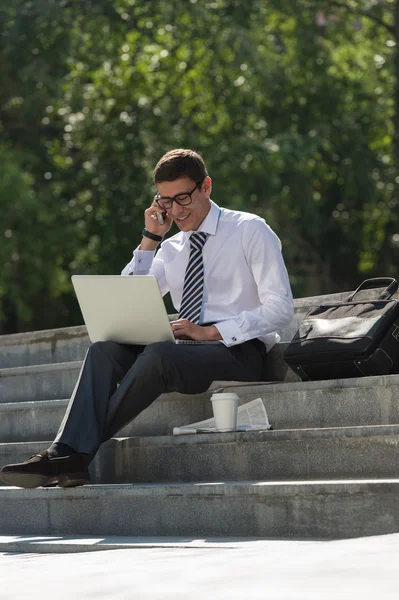 Man met laptop bellen via de telefoon — Stockfoto