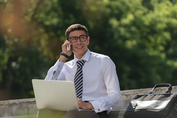 Man med laptop ringer via telefon — Stockfoto