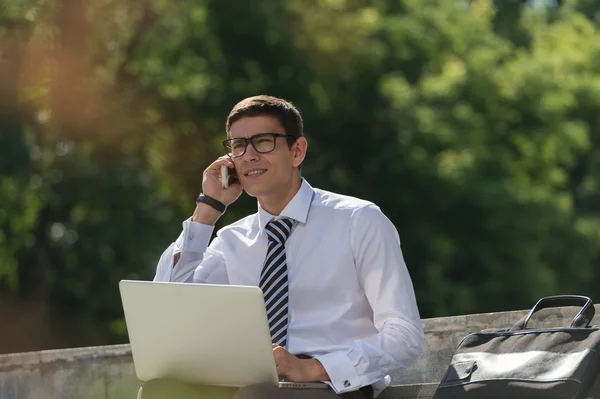 Man met laptop bellen via de telefoon — Stockfoto