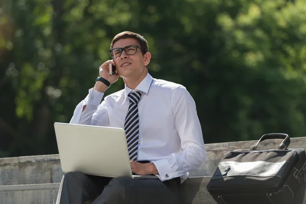 Man med laptop ringer via telefon — Stockfoto