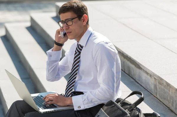 Homem com laptop chamando por telefone — Fotografia de Stock