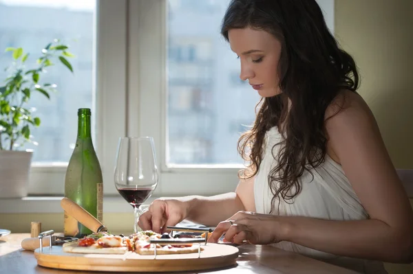 Frau isst Pizza und trinkt Wein — Stockfoto