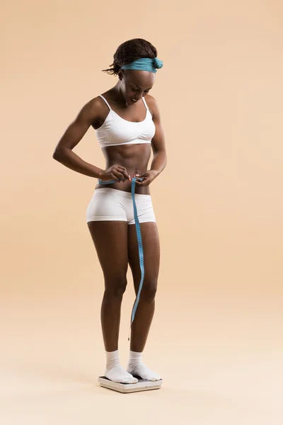Mujer de pie a escala midiendo cintura con cinta adhesiva — Foto de Stock